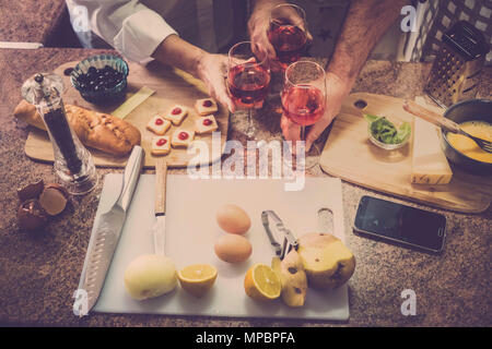Tre persone vicino a mani sul tavolo durante un tempo di cottura a casa con la famiglia e gli amici. molti cibi crudi e il telefono cellulare. Foto Stock