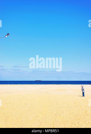Bambino e carta aquilone sopra l'Oceano Atlantico shore a Sandy Hook con una vista della città di New York. Sandy Hook è in New Jersey, USA. Foto Stock