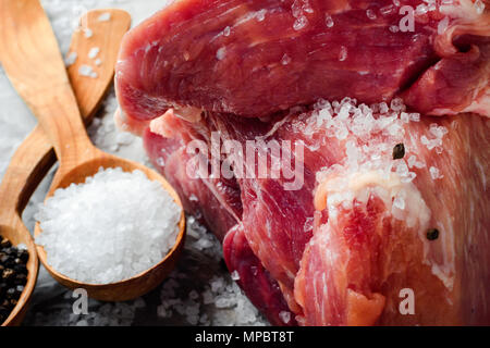 Un grande pezzo di fresco succosa carne cosparso con sale. Preparazione di carni per friggere le bistecche. Foto Stock