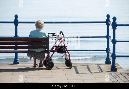 Anziani donna seduta su un banco da lavoro che si affaccia sul mare. Regno Unito Foto Stock