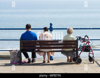 Donna anziana e coppia giovane seduto su un banco da lavoro che si affaccia sul mare. Regno Unito Foto Stock