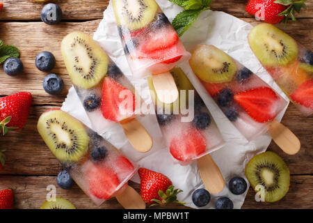 Bacca naturale di frutta da ghiaccio con fragole fresche, mirtilli e kiwi vicino sul tavolo. parte superiore orizzontale vista da sopra Foto Stock