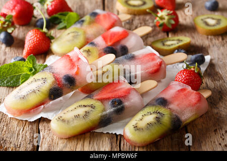 Congelati succhi di frutta con fragole, kiwi e mirtilli su un bastone vicino sul tavolo orizzontale. Foto Stock