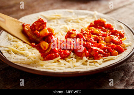 Realizzazione di quesadilla. Il riempimento è disteso sul tortilla. La cottura per sani e freschi quesadilla, tacos, buritto, fajita. Il concetto di national Foto Stock