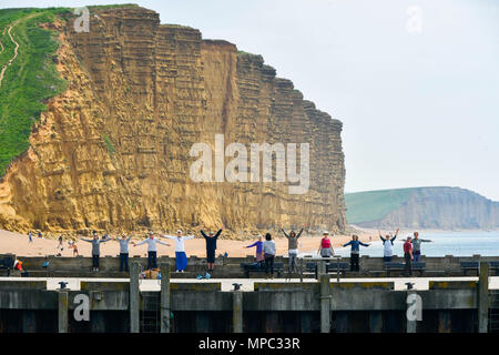 West Bay, Dorset, Regno Unito. 22 maggio 2018. Regno Unito Meteo. Un esercizio di gruppo sul molo Orientale con la mitica scogliere di arenaria dietro di loro, facendo il loro allenamento presso la località balneare di West Bay nel Dorset come godere di una calorosa soleggiata giornata di primavera. Credito Foto: Graham Hunt/Alamy Live News Foto Stock