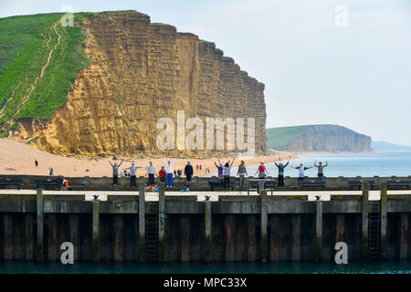 West Bay, Dorset, Regno Unito. 22 maggio 2018. Regno Unito Meteo. Un esercizio di gruppo sul molo Orientale con la mitica scogliere di arenaria dietro di loro, facendo il loro allenamento presso la località balneare di West Bay nel Dorset come godere di una calorosa soleggiata giornata di primavera. Credito Foto: Graham Hunt/Alamy Live News Foto Stock