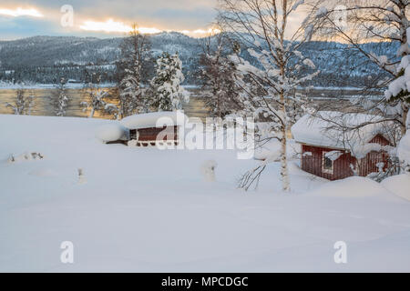 Paesaggio invernale in Tjåmotis con le montagne sullo sfondo, il sole che splende sulle montagne, creek con acqua aperta, sky con bei colori che riflettono in t Foto Stock