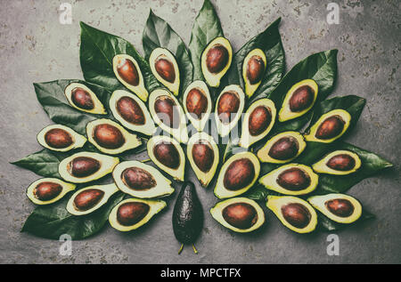 Peacock realizzato da avocado la palta e avocado foglie intorno la piastra nera. Guacamole ingredienti. Grassi sani, omega 3. La metà di avocado. Vista superiore Foto Stock