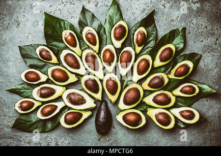 Peacock realizzato da avocado la palta e avocado foglie intorno la piastra nera. Guacamole ingredienti. Grassi sani, omega 3. La metà di avocado. Vista superiore Foto Stock