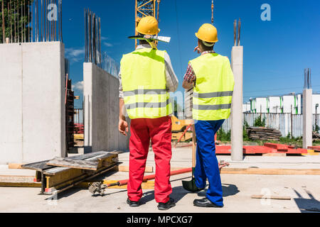 Due lavoratori indossare attrezzature di sicurezza durante i lavori di pianificazione Foto Stock