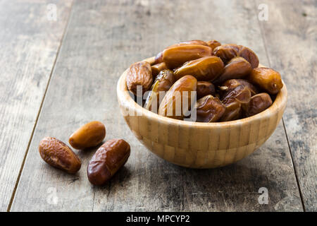 Date cibo nella ciotola di legno sul tavolo di legno Foto Stock