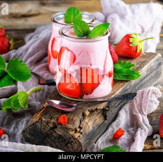 I frullati di fragole fresche e yogurt in un vasetto di vetro sul grigio di una tavola di legno Foto Stock