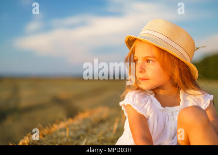 Bambina in un campo con rotoli di fieno Foto Stock