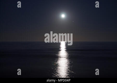 Grande luna piena è salita al di sopra del mare di notte. Luce lunare si riflette sull'acqua. Percorso lunare e oceano. Foto Stock