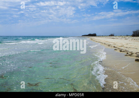 Il deserta fiaba spiaggia con sabbia dorata e acque azzurre sulle rive dell'oceano. Un posto romantico vicino al mare. Giorno nuvoloso. Foto Stock