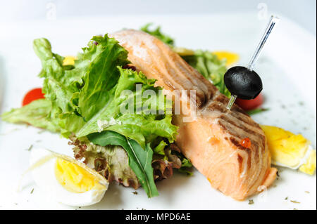 Salmone alla griglia con lattuga su una piastra bianca. Foto Stock