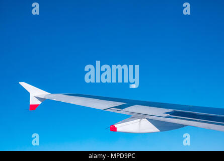 British Airways Airbus 319 ala piano scintillante di sole, visto dalla finestra del piano durante il volo con il cielo azzurro in UK e visibile della luna Foto Stock