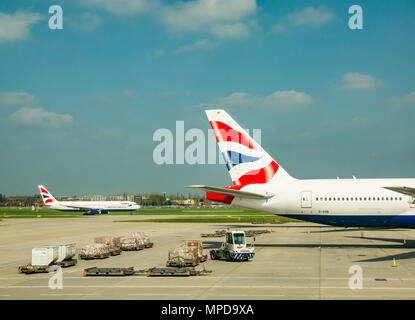 British Airways piani, compreso un Boeing 777 su airport grembiule con veicoli aeroportuali, terminale 5, l'aeroporto di Heathrow di Londra, Inghilterra, Regno Unito Foto Stock