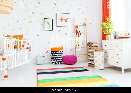 Luce baby room con cassettiera bianca e colorata rug Foto Stock