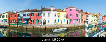 Panorama di case colorate su un canale nel villaggio di pescatori sull'isola di Burano, Venezia, Veneto, Italia con riflessioni sull'acqua ancora nei primi mesi del Foto Stock