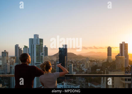 Giovane guardando al di sopra dello skyline della città con il Cielo di tramonto dal grattacielo bilding Foto Stock