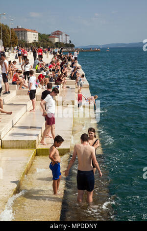 Villeggianti e turisti rilassante godendo il sole seduti sul lungomare dall'organo di mare nella costa adriatica resort di Zadar croazia Foto Stock