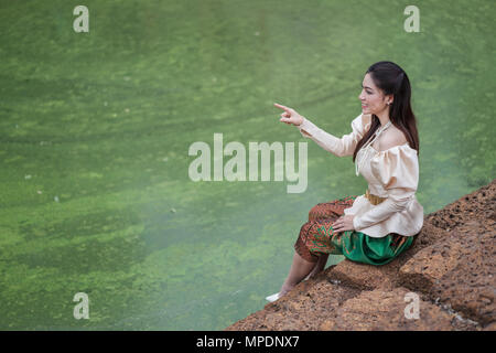 Bella donna inThai abito tradizionale è rivolto vicino al laghetto Foto Stock