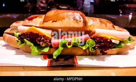 Sandwich croissant con prosciutto, formaggio cheddar, Cherry Pomodoro e verdi. fast food concept. Foto Stock