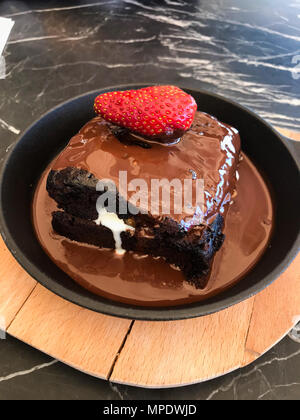 La crema riempiti a caldo Torta al cioccolato brownie con Fragola in padella servita al ristorante. Concetto di dessert. Foto Stock