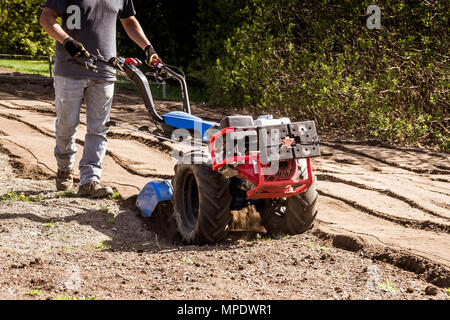 Coltivatore rototiller unità trascinamoduli preparazione del terreno sporco sul giardino esterno Foto Stock