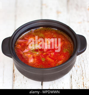 Red borsch. Il tradizionale piatto ucraino. In una piccola padella. Sul tavolo bianco Foto Stock