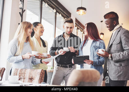 Il successo di giovani uomini di affari che stanno parlando e sorridente durante la pausa caffè in ufficio Foto Stock