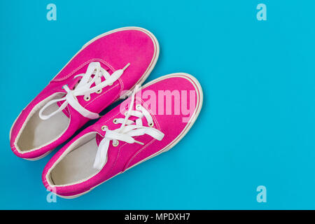Rosa sneakers con lacci su uno sfondo blu Foto Stock