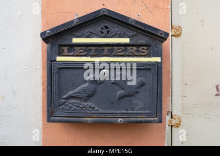 Nero metallo vintage cassetta postale con un bassorilievo di piccioni, parete rosa con strisce bianche di vernice sui lati. Foto Stock