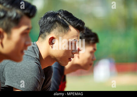 Close-up di facce di giovani asiatici guide adulti sulla linea di partenza. Foto Stock