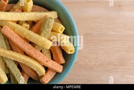 Top vista ravvicinata di un verde ciotola riempita veggie cannucce su una tavola di legno. Foto Stock