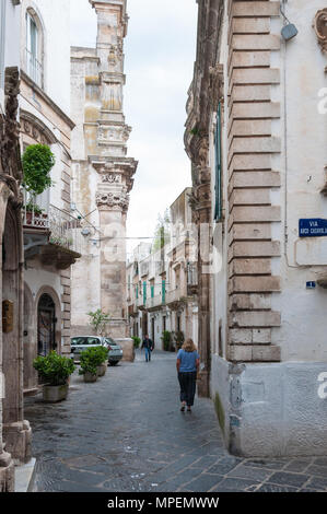 Una donna sola passeggiate lungo Via Principe Umberto verso la chiesa di San Domenico, Martina Franca, Puglia, Italia. Foto Stock