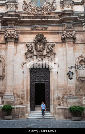 Una donna sola salite i gradini all'ingresso di La Chiesa di San Domenico, Martina Franca, Puglia, Italia. Foto Stock