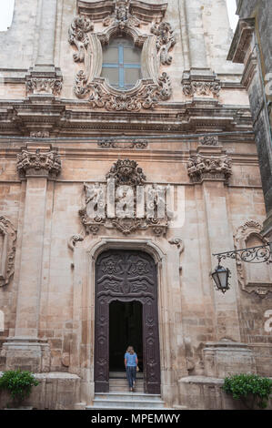 Una donna sola salite i gradini all'ingresso di La Chiesa di San Domenico, Martina Franca, Puglia, Italia. Foto Stock