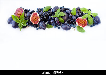 Blu e viola il cibo. Gruppo di frutta fresca e bacche con Basilio su uno sfondo bianco. Mirtilli maturi, more e uva, prugne e fichi. A Foto Stock