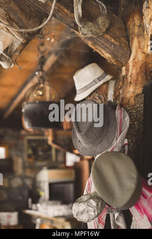 Dettaglio dettaglio di alcuni vecchi cappelli pende da una trave in una vecchia azienda agricola capannone girato ristorante Foto Stock