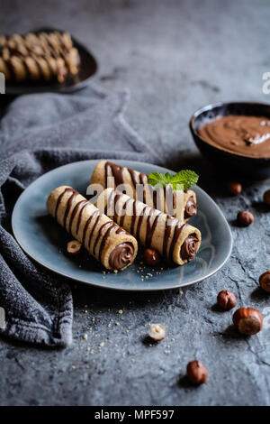 Deliziosi biscotti tubi riempiti con crema di nocciole e cioccolato topping Foto Stock
