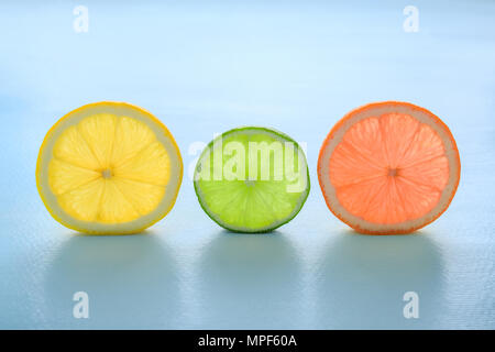 Traslucido fette di arancia lime limone e pompelmo pastello su sfondo blu. La minima nozione d'estate. Vista laterale, luminosi colori alla moda. Foto Stock