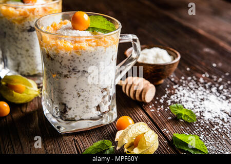 Yogurt probiotici con semi di Chia, noce di cocco, miele e physalis purea in un vasetto di vetro Foto Stock