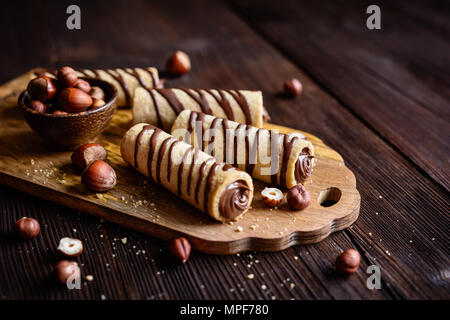Deliziosi biscotti tubi riempiti con crema di nocciole e cioccolato topping Foto Stock