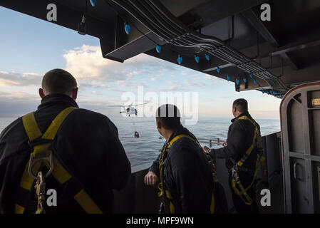 170218-N-WG055-006 mare mediterraneo (feb. 18, 2017) marinai guarda un MH-60S Sea Hawk elicottero da combattimento del mare Squadron (HSC) 9, il Tridents, come si muove il carico per il ponte di volo della portaerei USS George H.W. Bussola (CVN 77) durante un rifornimento in mare (RAS). Il George H.W. Bush Strike gruppo sta attualmente conducendo operazioni navali negli Stati Uniti Flotta di 6 aree di intervento a sostegno di funzionamento inerenti a risolvere. (U.S. Foto di Marina di Massa Specialista comunicazione marinaio apprendista Kyle A. Moore/rilasciato) Foto Stock