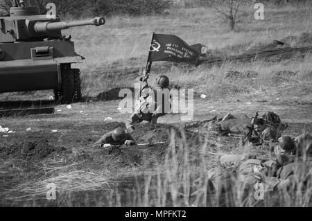 2018-04-30 La Samara, Russia. L offensiva di soldati dell'esercito sovietico con una bandiera sulla posizione delle truppe tedesche. La ricostruzione di hostil Foto Stock