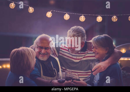 Focus sull'uomo. gruppo di anziani di età adulta facendo parte della notte sul tetto di casa. abbraccio tutti insieme e sorridere e ridere per un attività di nizza Foto Stock