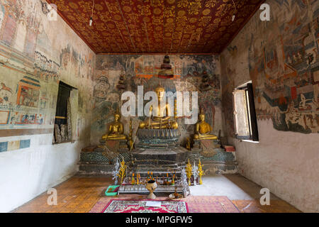Murales, altare e statue di Buddha all'interno di Wat Pa Huak tempio a Luang Prabang, Laos. Foto Stock