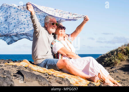 Coppia senior in amore per sempre insieme hanno gioia stare abbracciati sulla costa dell'oceano in Tenerife. godersi le vacanze con libertà e stile hippy vestiti. nic Foto Stock